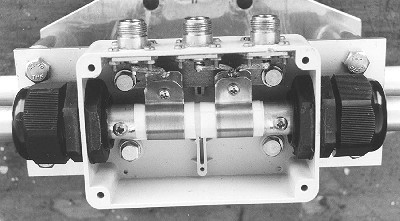 The feed connection box. Half-wave coaxial balun connected to the two outer N connectors and 50 ohm feeder to the centre N.  Note the two 50pf custom-made  capacitors feeding the T match arms.